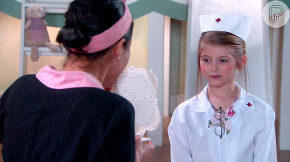 Vestida de enfermeira, Dulce Maria (Lorena Queiroz) pede para Franciely (Carol Loback) maquiá-la, na novela 'Carinha de Anjo'