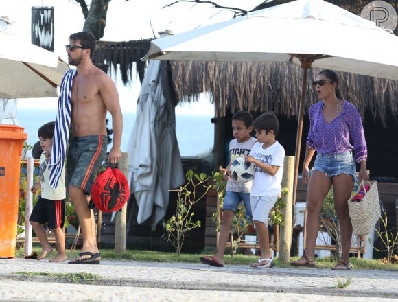 Juliana Paes atravessa calçadão da praia da Barra da Tijuca com marido e filhos