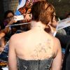 Scarlett Johansson exibe tatuagem nas costas ao dar autógrafos em première