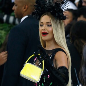 Rita Ora ornou vestido preto fluído com bolsa amarela 