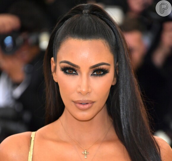 Kim Kardashian apostou no penteado rabo de cavalo superalto e adotou lentes de contato marrom