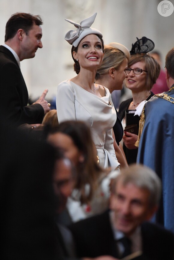 Angelina Jolie elege como adereço broche dourado e chapéu casquete 