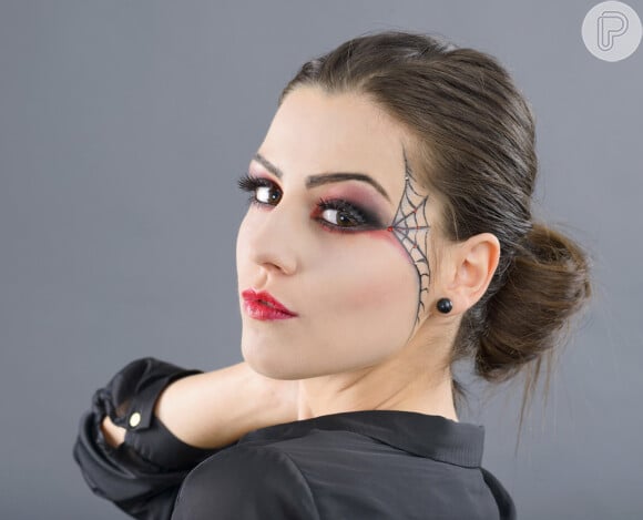 A maquiagem com teia de aranha para o Halloween pode ser feita com lápis de olho preto e com pedras de strass nas pontas
