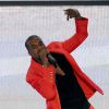 Kanye West surgiu como DJ vestindo um terno vermelho, em um fundo minimalista em branco e preto