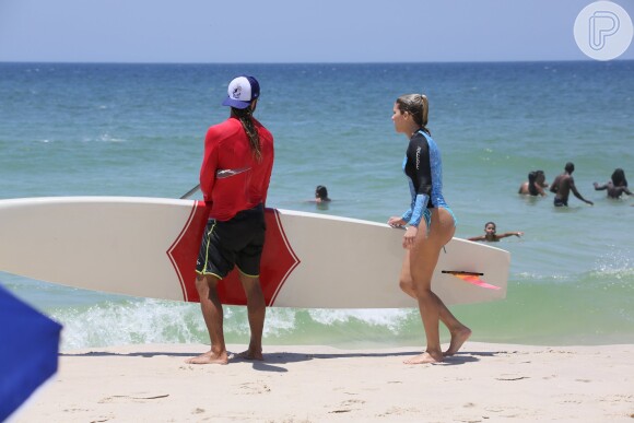 Isabella Santoni e o namorado, Caio Vaz, levam a prancha de stand-up paddle para a areia juntos