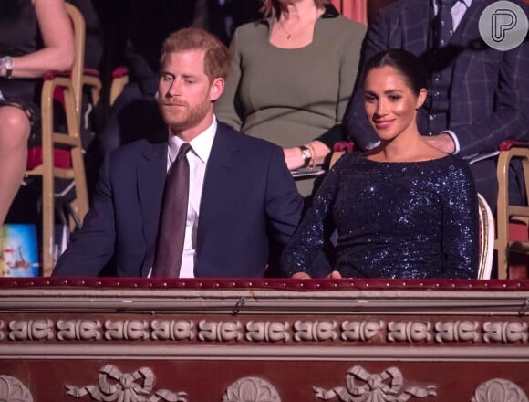 Com look inspirado na princesa Diana, Meghan Markle quebra protocolo com Harry em espetáculo beneficente ao segurar a mão do marido na quarta-feira, dia 17 de janeiro de 2019

