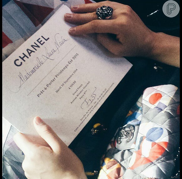 Laura Neiva exibe o convite do evento da grife Chanel