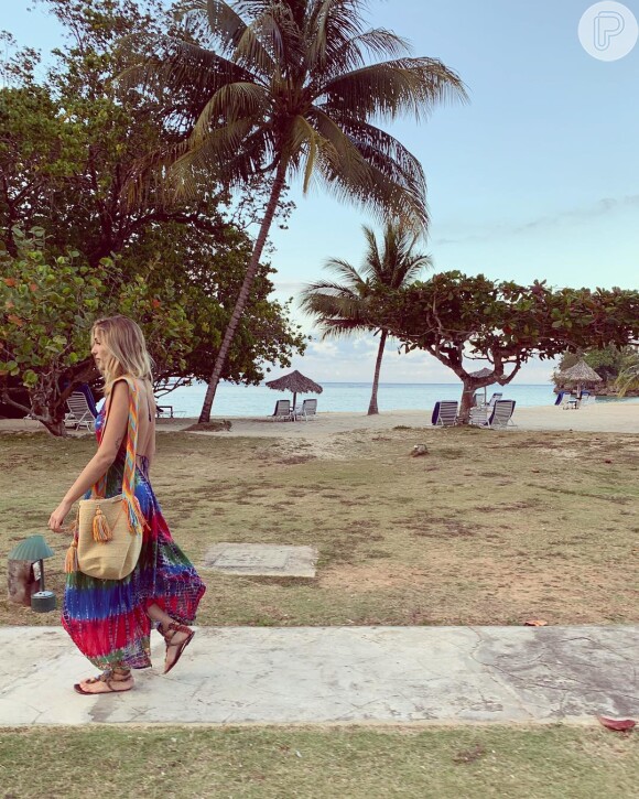 Sasha Meneghel aposta na trend tie dye em vestido pós-praia em cores vibrantes. A bolsa de palha saco com alças coloridas complementaram a produção
