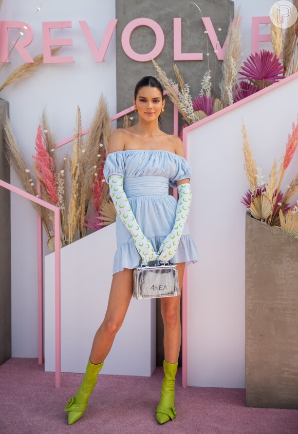 Look Coachella 2019: é claro que Kendall Jenner não ficaria de fora. Ela usou luvas compridas, dando uma pegada anos 50 na produção, vestido com decote bardot ombro a ombro em tom de azul pastel e bota de bico fino e cano curto em tom de verde-limão