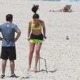 Anitta é observada por seu personal trainer durante exercício na praia da Barra da Tijuca