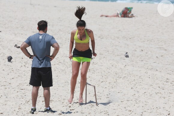 Anitta é observada por seu personal trainer durante exercício na praia da Barra da Tijuca
