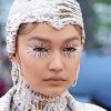 Gigi Hadid optou por uma touca cravejada de cristais em tons de branco, prata e dourado para o seu look pra lá de futurista