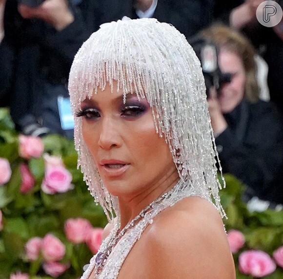 Jennifer Lopez sabe como ninguém atrair a atenção dos holofotes! A cantora escolheu a touca cravejada de cristais para combinar com seu look prateado Versace