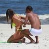 Nicole Bahls precisa da ajuda de um amigo para amarrar seu biquíni, na praia da Barra da Tijuca, no Rio