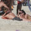 Grazi Massafera se bronzea com biquíni desamarrado e conversa com amiga em praia