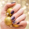 Dourado é uma das cores do Natal. Se quiser uma nail art discreta, adicione um detalhe do esmalte em apenas uma das unhas