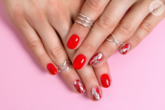 O clássico esmalte vermelho de Natal pode ganhar um toque glam com o esmalte prata por cima de duas unhas