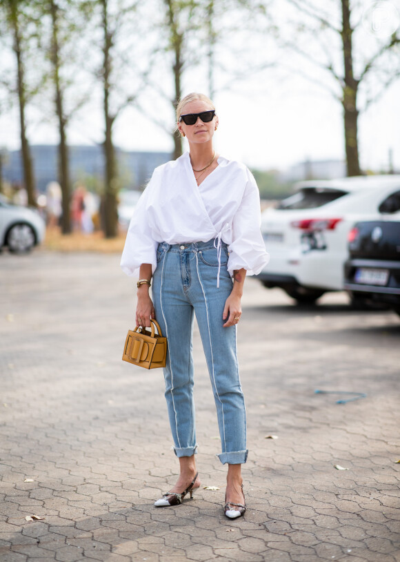 Moda jeans: a calça em denim pode ser aliada à blusa transpassada branca com mangas volumosas para look fashionista