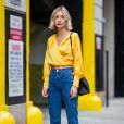 Calça jeans na moda: a blusa amarela transpassada de seda - tecido em alta no streetwear - dá um ar glam ao look do dia a dia