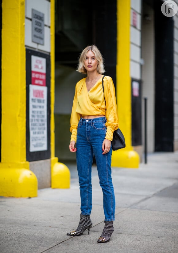 Calça jeans na moda: a blusa amarela transpassada de seda - tecido em alta no streetwear - dá um ar glam ao look do dia a dia