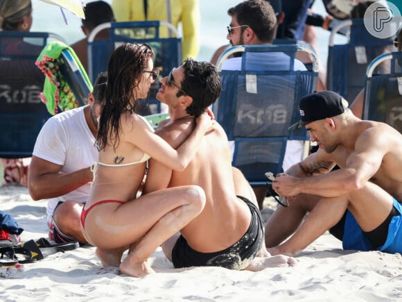 Isis Valverde e o marido, André Resende, se beijam em momento de lazer na praia