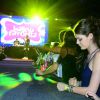 Laura Neiva mexe no celular encostada no palco durante o Baile da Favorita