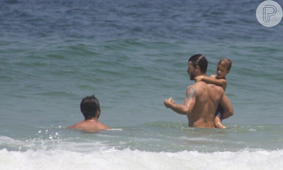 Rodrigo Hilbert aproveita as ondas com o filho, em seu colo