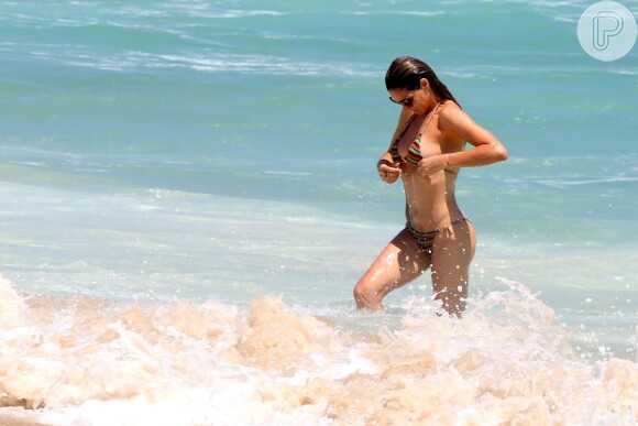 Fernanda Lima ajeita biquíni depois do banho de mar