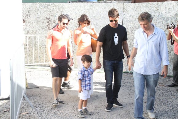 Estiloso de xadrez e bermudão, Pedro aparece de mãos dadas com seu pai, Carlos Eduardo Baptista, em um evento no Rio de Janeiro