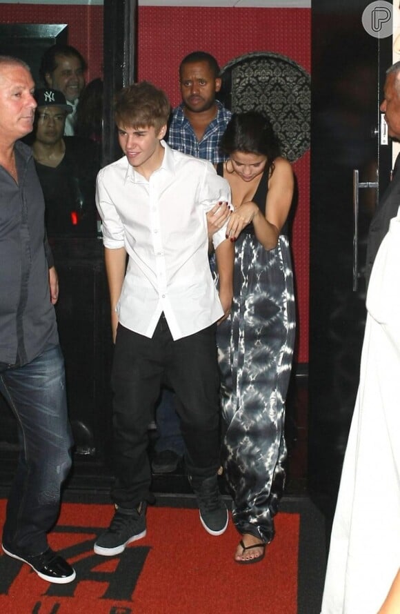 Selena Gomez junto ao namorado Justin Bieber, em 2011, em um restaurante em Copacabana. A cantora visivelmente incomodada com a ação dos paparazzi