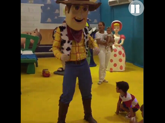 Enquanto a mãe brinca com amigos, Pedro dança com o cowboy Woody, personagem do filme 'Toy Story'