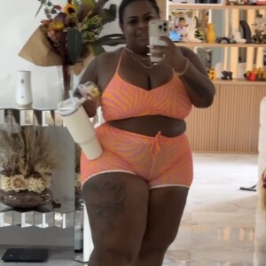 Jojo Todynho usa conjunto composto por short e top laranja neon com listras roxas para ir malhar