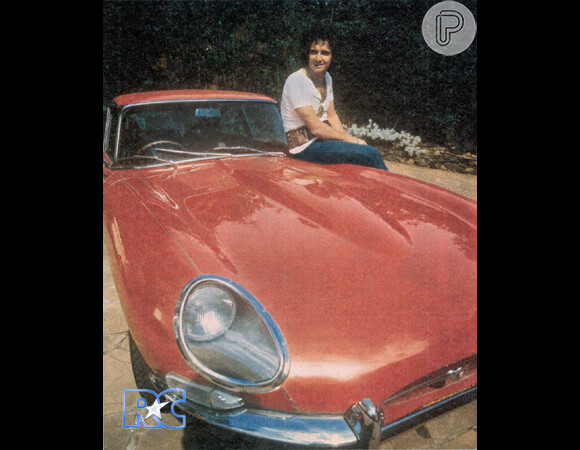 Roberto posa ao lado de um Jaguar E-Type na cor vermelho