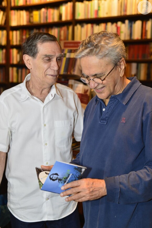 Caetano Veloso, ao lado de Jorge Mautner, olha o CD da trilha sonora