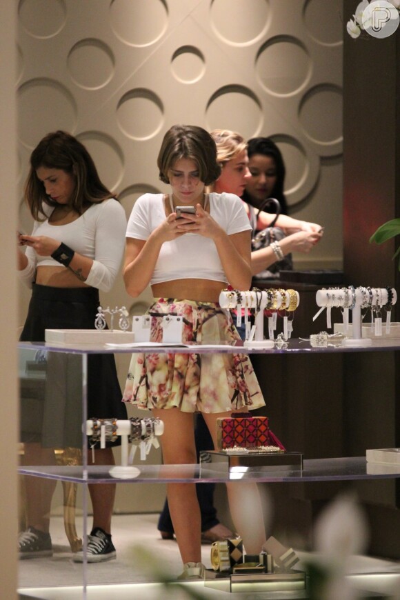 Isabella Santoni não deixou de lado seu celular durante passeio em shopping do Rio