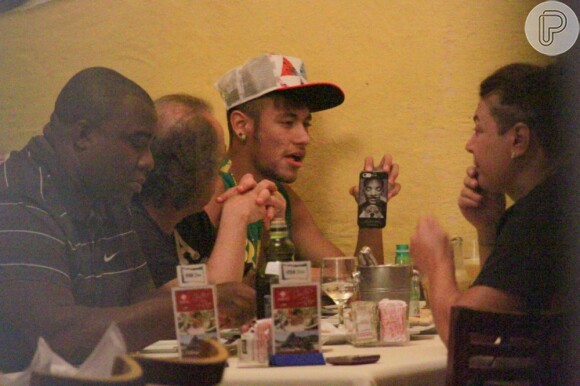 Neymar segura o celular enquanto almoça com os amigos em churrascaria