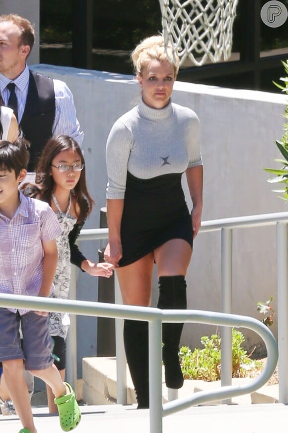 Britney Spears caminha segurando o vestido curto