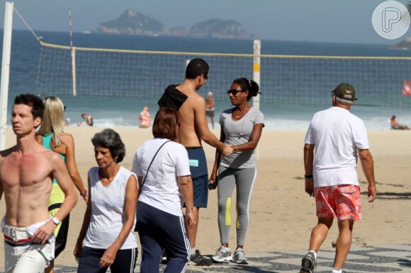 Glória Maria passeia pela orla da praia de Ipanema, encontra um amigo e recebe carinho