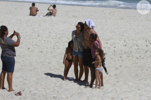 Bruno Gissoni e Yanna Lavigne posam para foto com fãs na praia da Barra da Tijuca