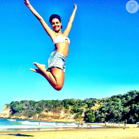 Paloma Bernardi mostra boa forma, fazendo salto na praia, de biquíni e shortinho