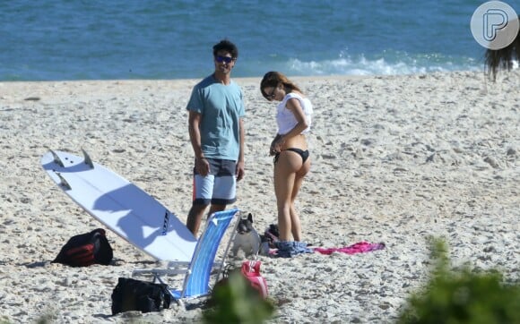 Isis Valverde ajeita o biquíni ao chegar na praia com o namorado, André Resende