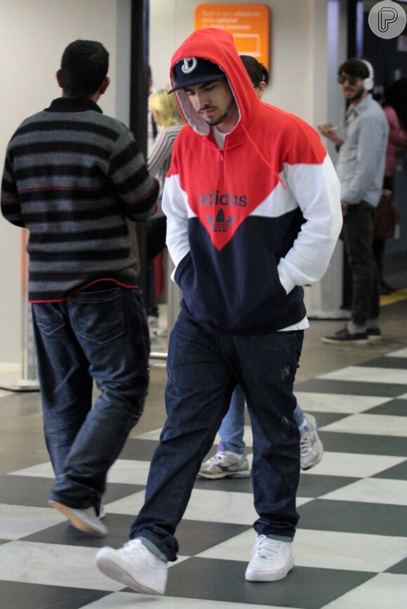 Caio Castro usa capuz do casaco para caminhar no aeroporto de Congonhas, em São Paulo