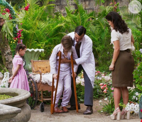 Usando muletas, Claudinho (Xande Valois) brinca com Alice (Nathália Costa) e Pirulito (JP Rufino), e é observado por Araújo (Flávio Tolezani) e Olga (Maria Carol), na novela 'Êta Mundo Bom!'