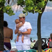 Marcelo Serrado brinca com um de seus filhos gêmeos em parquinho na praia