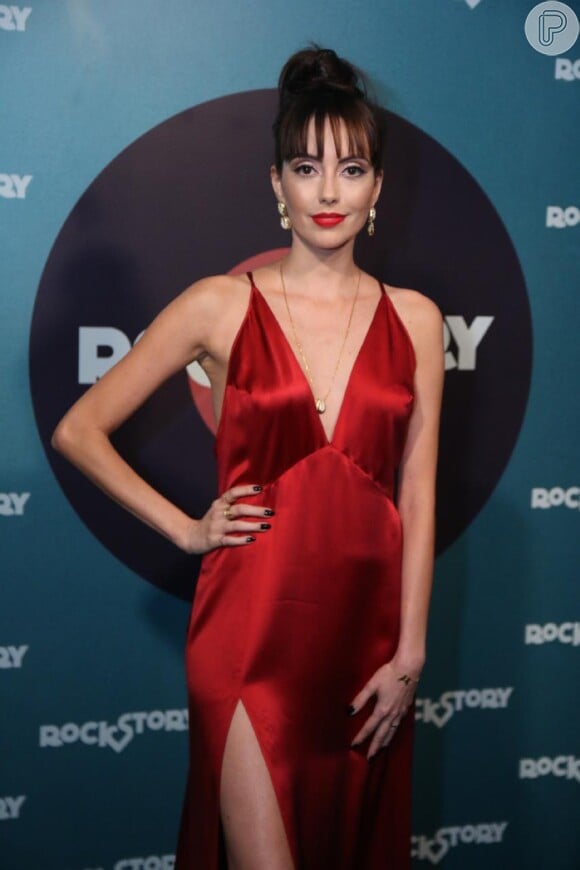 Mariana Vaz, mulher do ator Thiago Fragoso, atraiu os flashs ao desfilar com um longo vermelho com superdecote e fenda lateral da Reformation