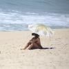 Alinne Moraes, grávida de cinco meses, fica na areia sozinha enquanto seu namorado, Mauro Lima surfa