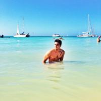 Luan Santana toma banho em praia no Caribe exibindo músculos e tatuagem de terço
