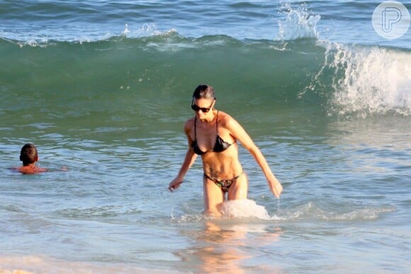 Fernanda Lima sai do mar e exibe a barriga sarada de biquíni