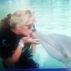 Adriane Galisteu beija golfinho em parque aquático nas Bahamas enquanto segura seu filho, Vittorio, de 2 anos, no colo, em 11 de janeiro de 2013