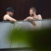 David Beckham, sem camisa, conversa com amigo em sacada de hotel
